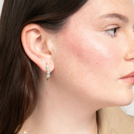 Close-up of a woman wearing a 14k gold filled J hoop earring with four small round amazonite gemstones.