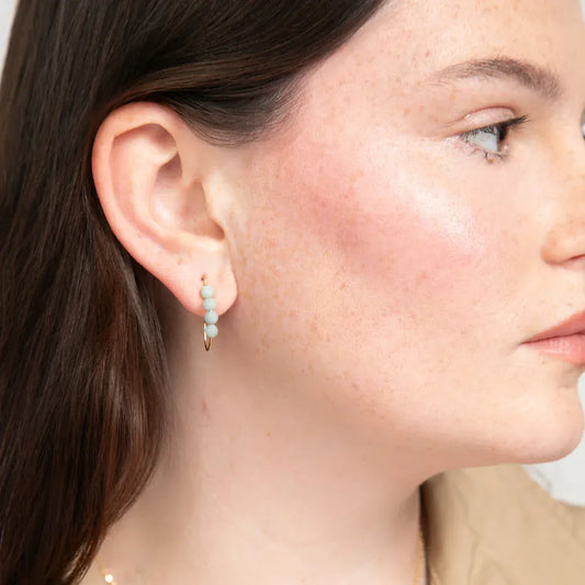 Close-up of a woman wearing a 14k gold filled J hoop earring with four small round amazonite gemstones.