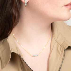 Close-up of woman in beige zippered top wearing a minimalist14k gold filled necklace with four amazonite gemstones. Close-up of woman in beige zippered top wearing a minimalist14k gold filled necklace with four amazonite gemstones.