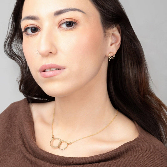 A young woman wearing Zomi Open Circle Earrings and Zomi Circles of Unity Necklace in 14k gold filled.
