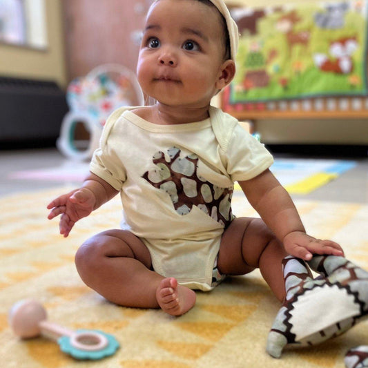 A natural baby onesie with hand-appliquéd giraffe design on the front.