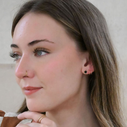 close up of a model wearing stud earrings made of a black onyx bead encircled in 14 karat gold filled wire