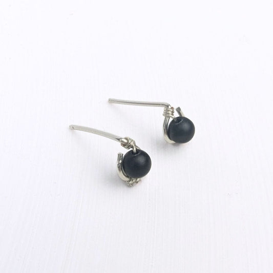 close up of model wearing a stud earring featuring a black onyx bead encircled in sterling silver