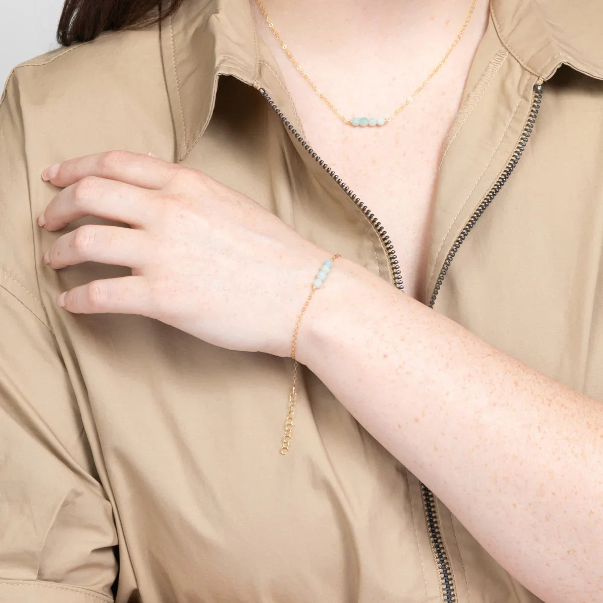 Woman in beige shirt wearing 14k gold fillled bracelet with four amazonite beads.
