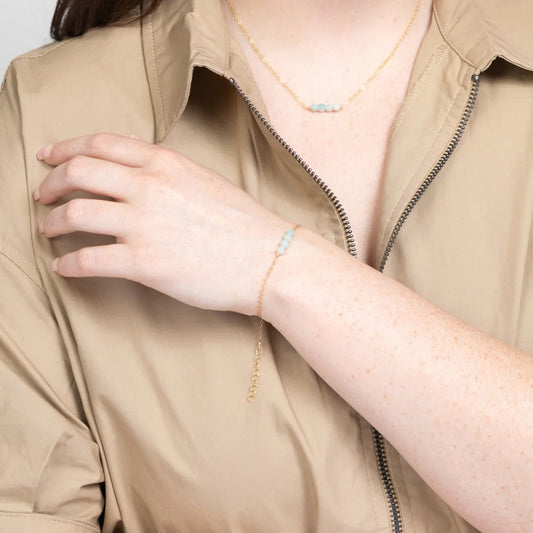 Woman in beige shirt wearing 14k gold fillled bracelet with four amazonite beads.