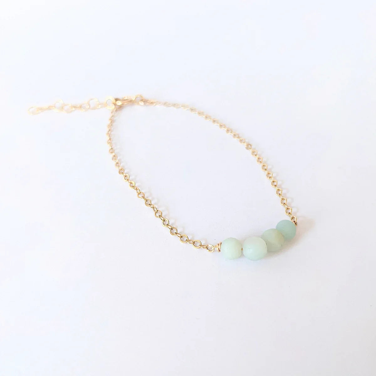 A 14k gold filled chain bracelet with four green amazonite beads on a white background.
