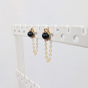 a pair of gold stud earrings on a display rack with dainty chain earring jackets attached to form loops. a pair of gold stud earrings on a display rack with dainty chain earring jackets attached to form loops.
