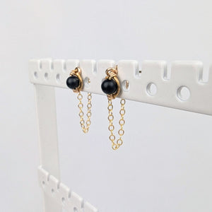 a pair of gold stud earrings on a display rack with dainty chain earring jackets attached to form loops. a pair of gold stud earrings on a display rack with dainty chain earring jackets attached to form loops.
