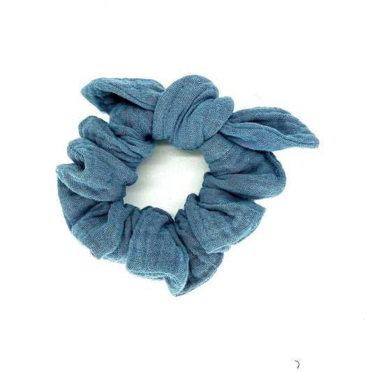 A handmade dusty blue double cotton gauze scrunchie on a white background.