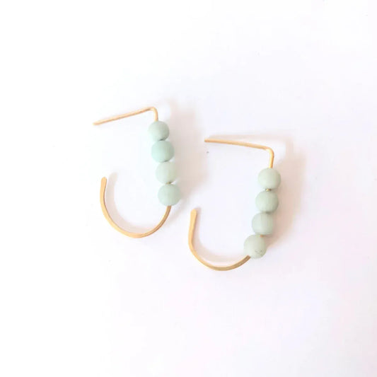 Close-up of a woman wearing a 14k gold filled J hoop earring with four small round amazonite gemstones.