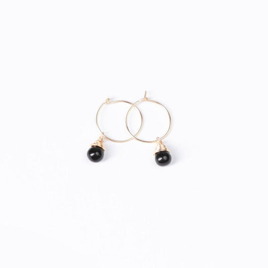 A woman in red wearing the Mini-hoop Midnight Black Charm Earrings with 14k gold filled hoops.