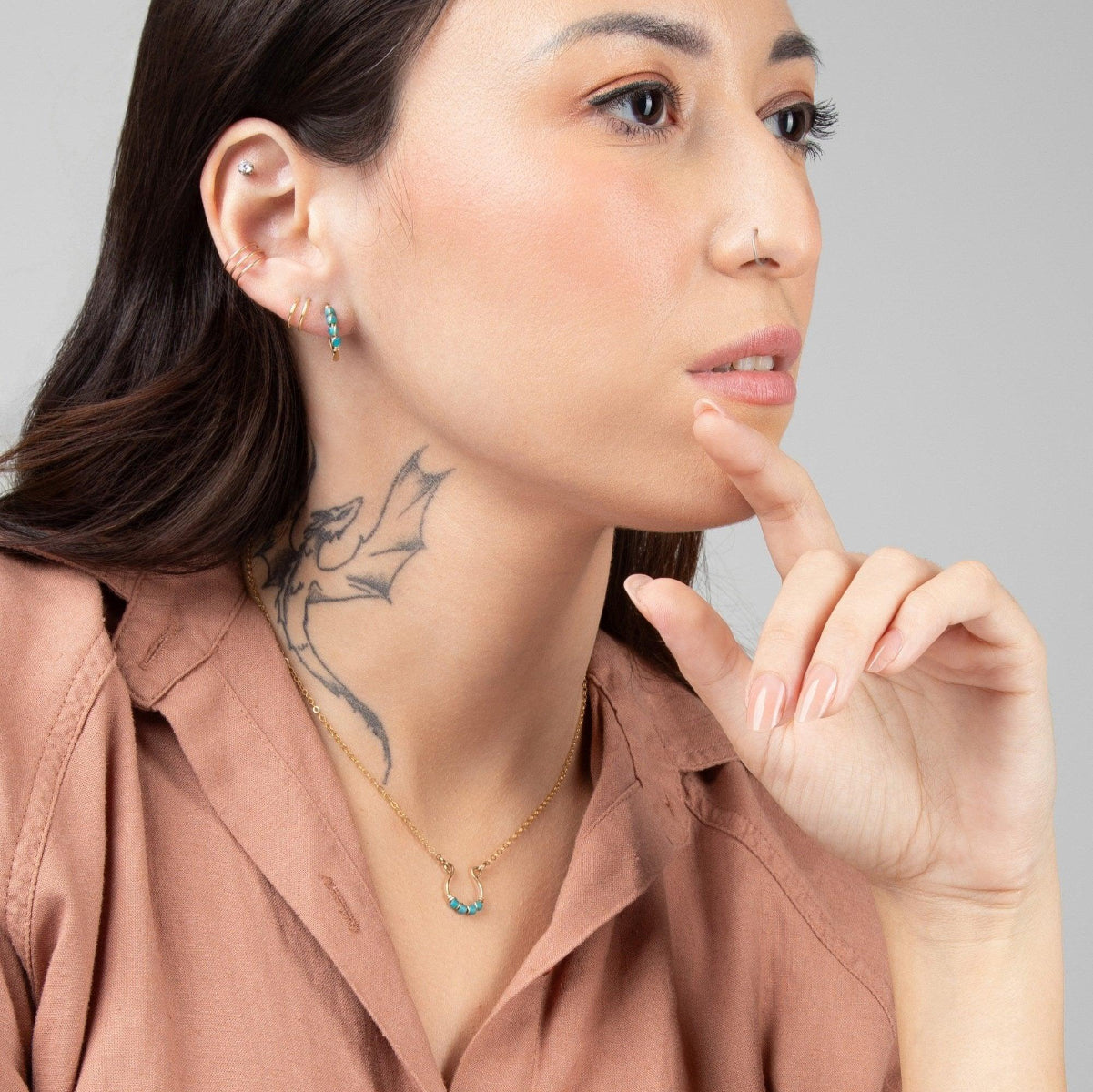Woman in beige blouse wearing Moab Western Beaded Earrings and Necklace in 14k Gold Filled. Horseshoe pendant wrapped with turquoise beads. Threader earrings.