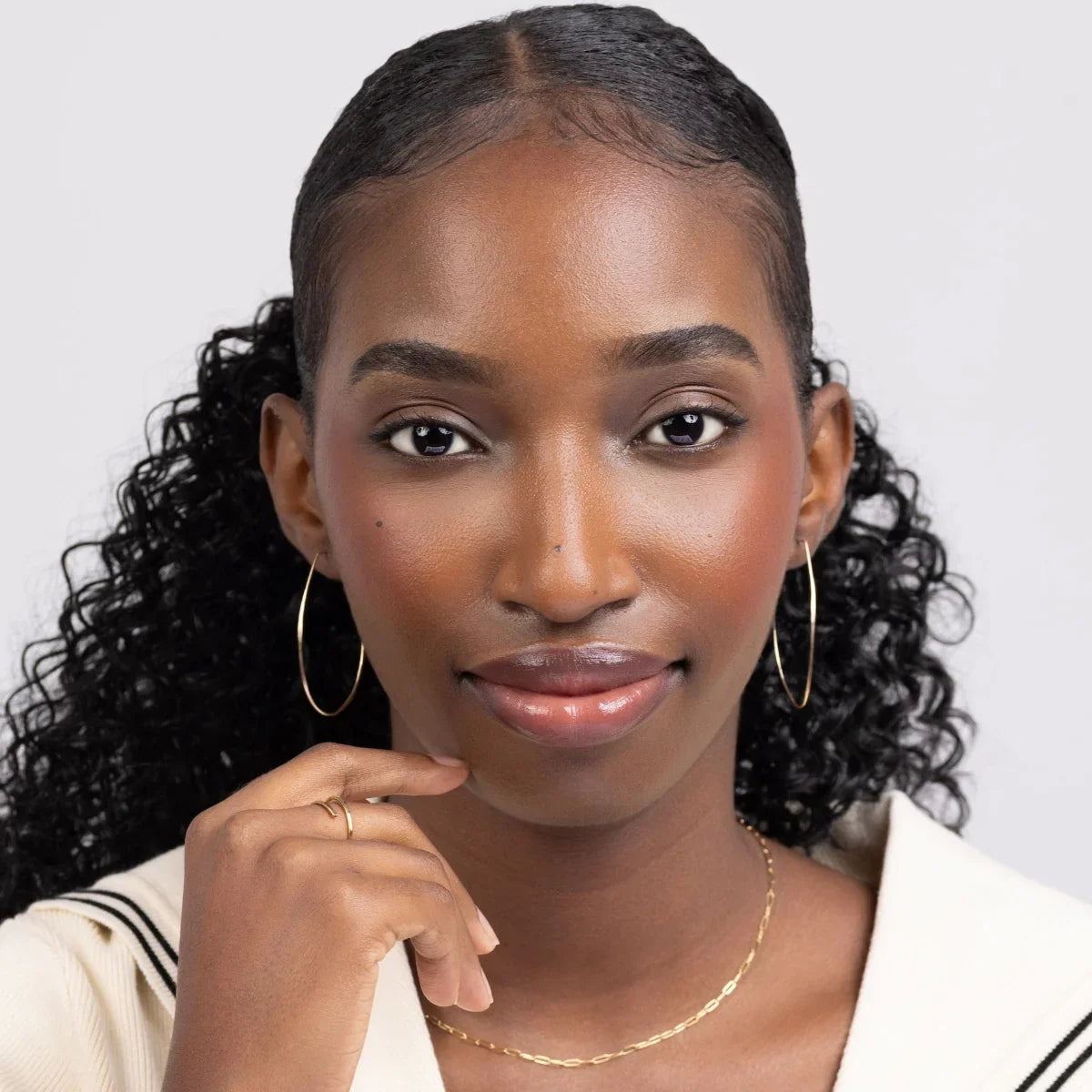 Woman in cream-colored cardigan wearing Azmera Hammered Hoop Earrings in 14k gold filled. Minimalist.