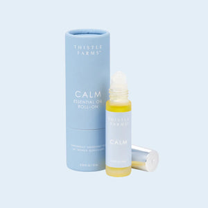 Thistle Farms Calm essential oil roll-on bottle and packaging on a light blue background Thistle Farms Calm essential oil roll-on bottle and packaging on a light blue background