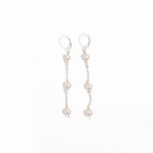 Woman in a blue pleated blouse wearing freshwater pearl triple drop leverback earrings in sterling silver