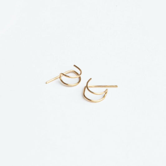 Woman in a blue denim shirt wearing Journey of Hope Huggie Earrings in 14k gold filled.