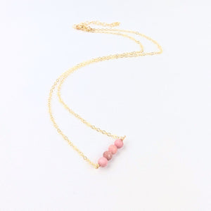 Necklace with pink beads on a gold chain against a white background Necklace with pink beads on a gold chain against a white background