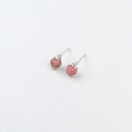 a pair of silver stud earrings with pink beads on a white background