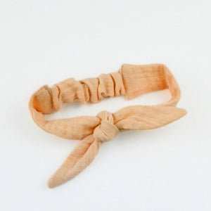 Peach-colored knotted headband on a white background Peach-colored knotted headband on a white background