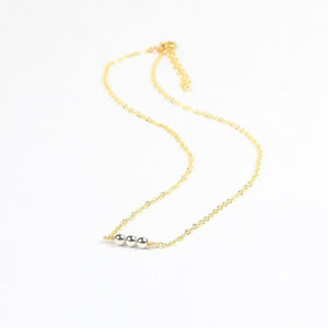 Gold necklace with three silver beads on a white background Gold necklace with three silver beads on a white background