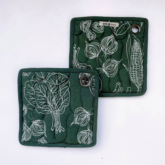 Two dark green quilted pot holders with white line-art vegetable prints, including leafy greens, onions, and corn, displayed on a white background.