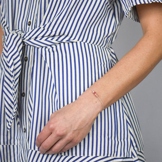 woman in a blue and white striped dress wearing a silver chain bracelet with four pink rhodonite beads in the center