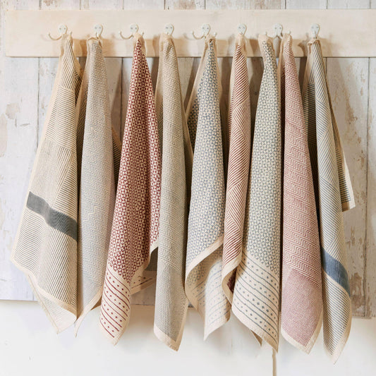 Textured towel with geometric pattern hanging on a wooden rod against a white background