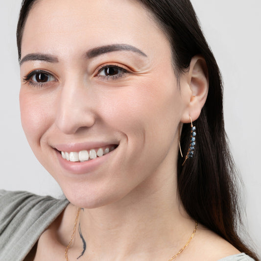 A smiling woman wearing the Mai Blue Beaded Threader Earrings in 14k Gold Filled.