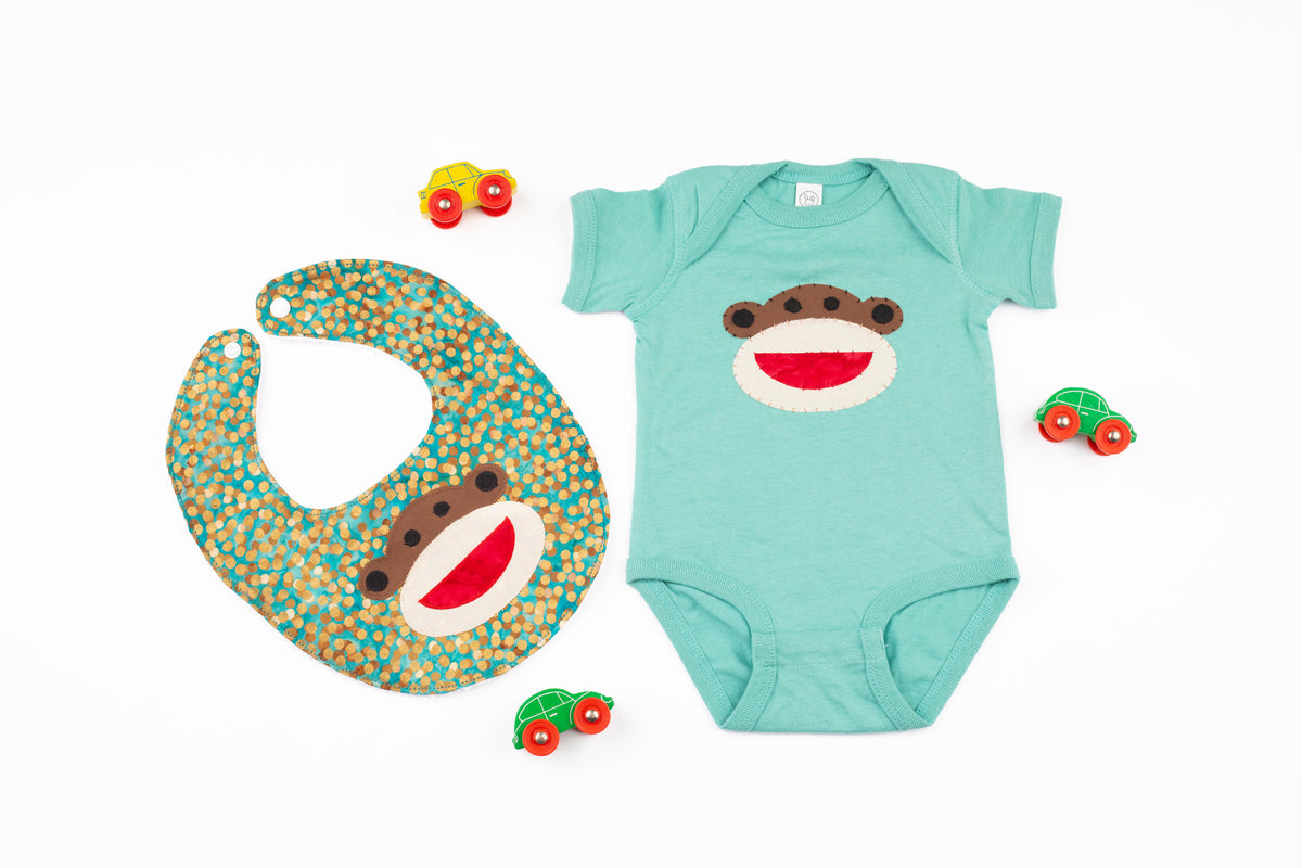 Baby onesie and bib with monkey design on a white background