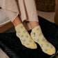 Person wearing yellow ankle socks with smiley faces.