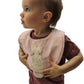 Child wearing a pink gingham bib with a handstitched bunny applique  on a white background
