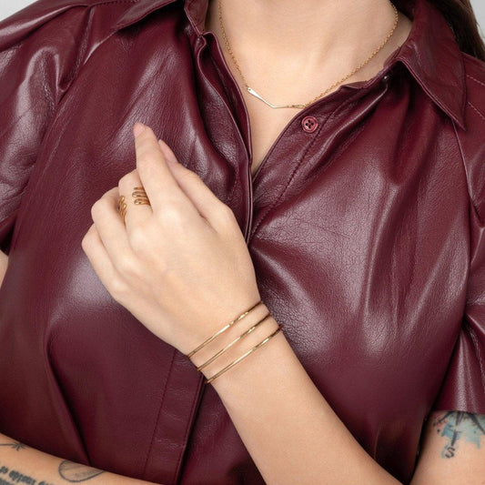 A woman in a red leather shirt showcasing the Journey of Hope Brass Bangle on her wrist.