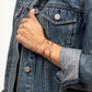 Arm of woman wearing denim jacket with an Emily Brass Bangle and two Hammered Brass Bangles, modern and minimalist.