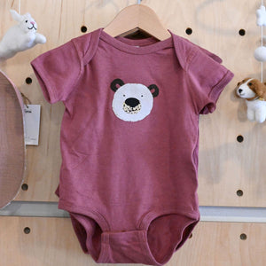 Rouge baby onesie with a hand appliqued bear face design in the center