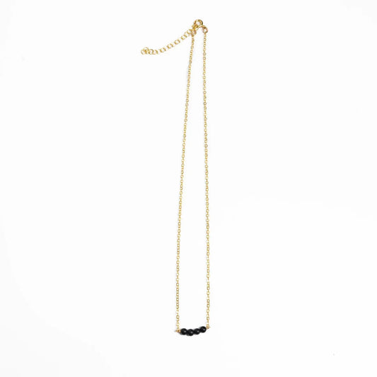 Woman in a black and white striped shirt wearing Jordan Black Onyx Necklace, Bracelet, and J Hoop Earrings in 14k gold filled.