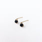 a pair of small gold stud earrings featuring black onyx beads encircled in 14 karat gold filled wire