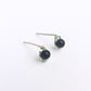 close up of a pair of sterling silver stud earrings featuring black onyx beads on a white background