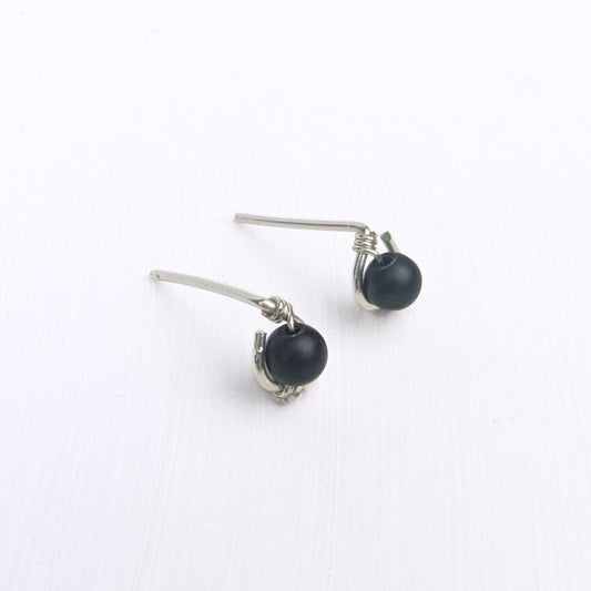 close up of model wearing a stud earring featuring a black onyx bead encircled in sterling silver