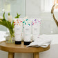 Three Thistle Farms body lotions on side table in front of bath tub.