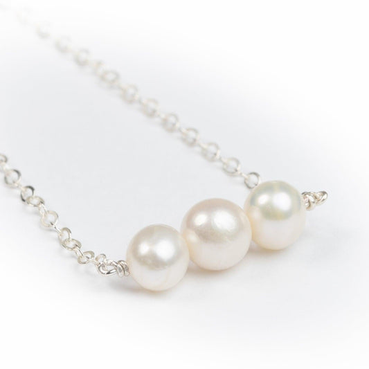 Smiling woman in black wearing the Leeda Freshwater Pearl Bracelet, Earrings and Necklace in Sterling Silver