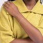 Woman in a yellow sweater wearing a sterling silver paperclip chain bracelet.