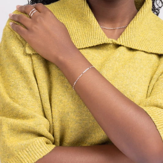 Woman in a yellow sweater wearing a sterling silver paperclip chain bracelet.
