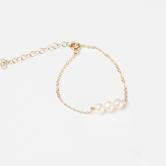 A woman showcasing the classic Leeda Freshwater Pearl Bracelet in 14k Gold Filled on her wrist.