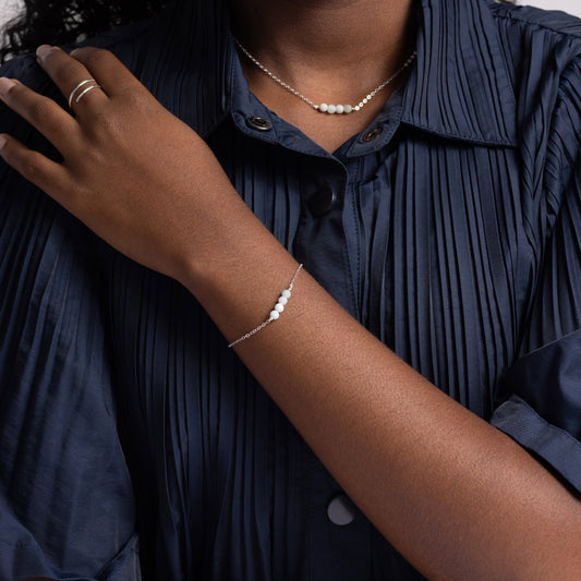 Woman in navy pleated shirt wearing the minimalist Jordan Amazonite Bracelet in sterling silver.