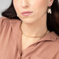 A woman in a brown shirt wearing a hammered brass collar necklace.