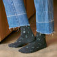 Person wearing dark gray socks with light blue musical note patterns and blue jeans.