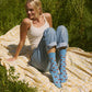 Young woman sitting on a blanket outdoors wearing blue crew socks with ladybug pattern.