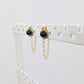 a pair of gold stud earrings on a display rack with dainty chain earring jackets attached to form loops.