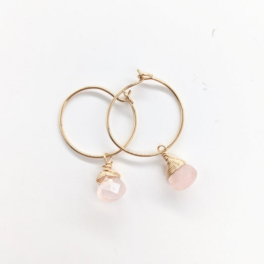 A woman wearing the Mini-hoop Rose Quartz Charm Earrings in 14k gold filled. The earrings are visible on her right ear.