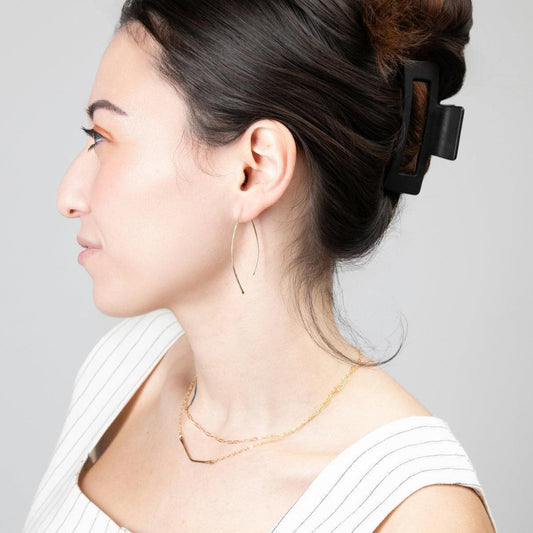 A woman wearing the Qasioun Minimalist Threader Earrings in 14k gold filled, with the earrings visible as they drop from her ear lobe.